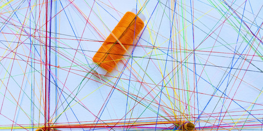 Vernetzung Weißer Hintergrund vor dem bunte Fäden an mehreren Punkten befestigt sind und sich mehrfach kreuzen.